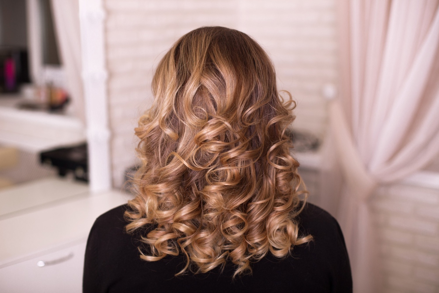 Female back with curly, ombre, brunette hair, in hairdressing salon